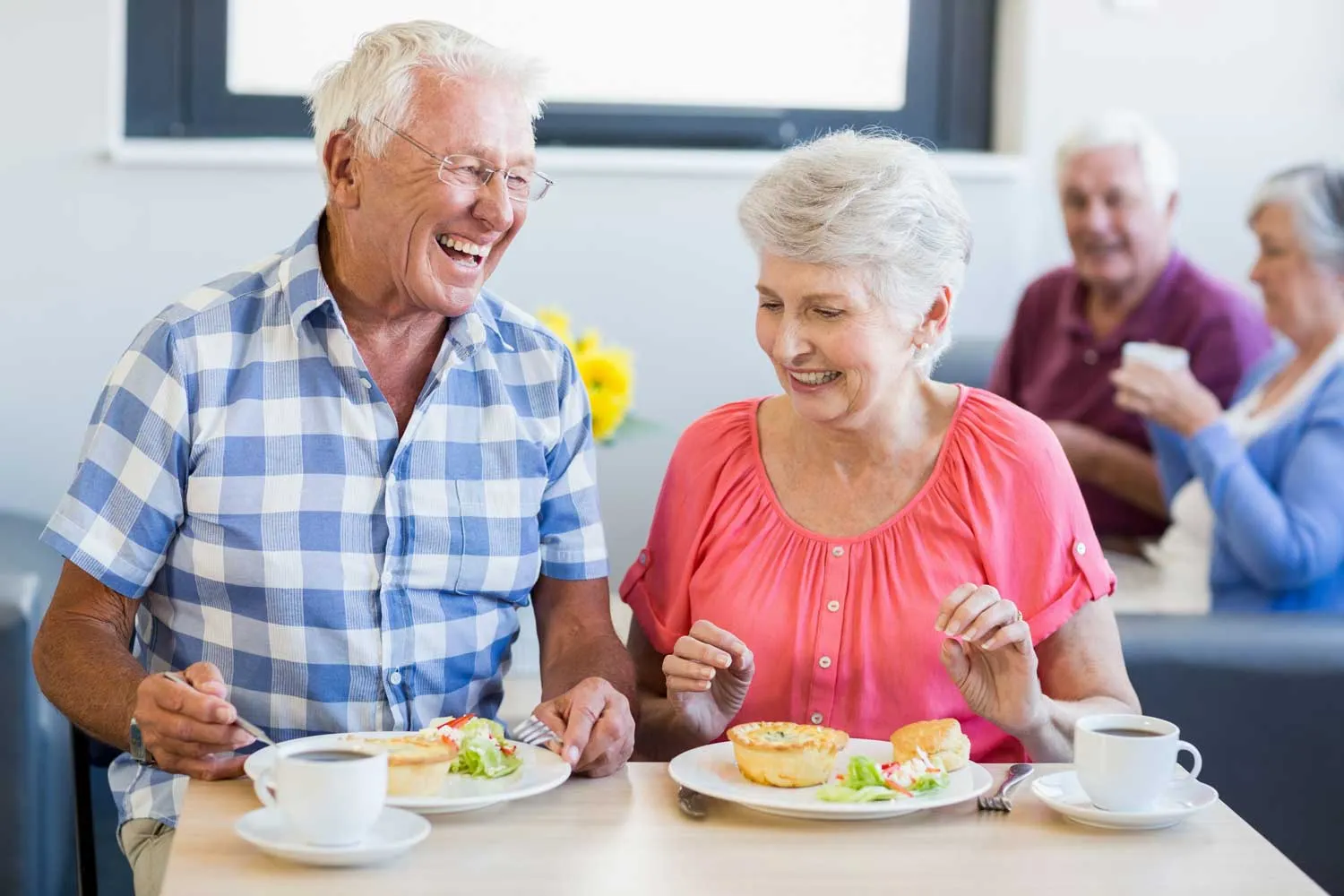 Seniors eating and smiling as part of senior wellness